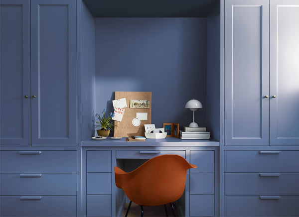 orange chair in front of blue cabinets